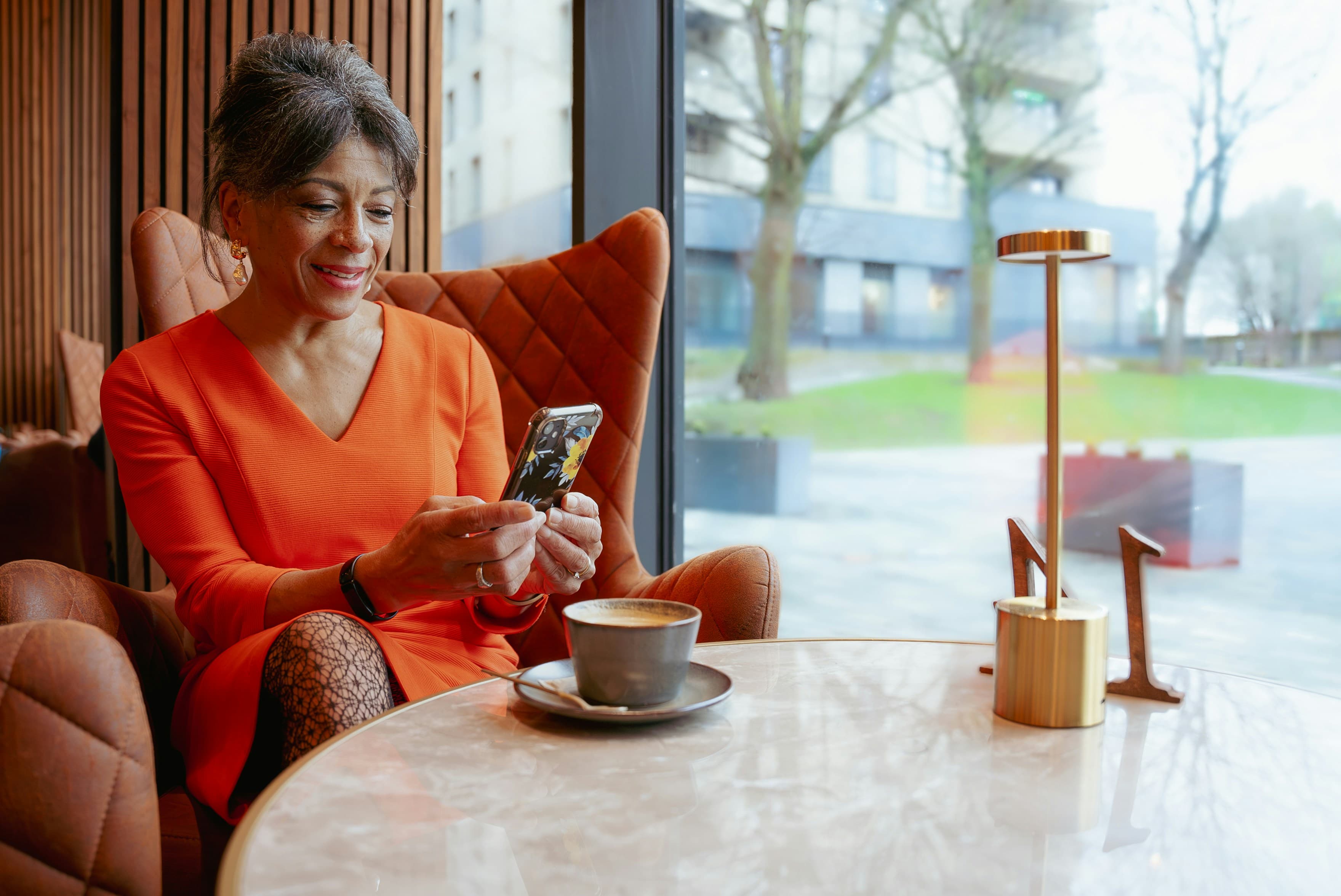 Woman smiling while looking at her phone in a cafe